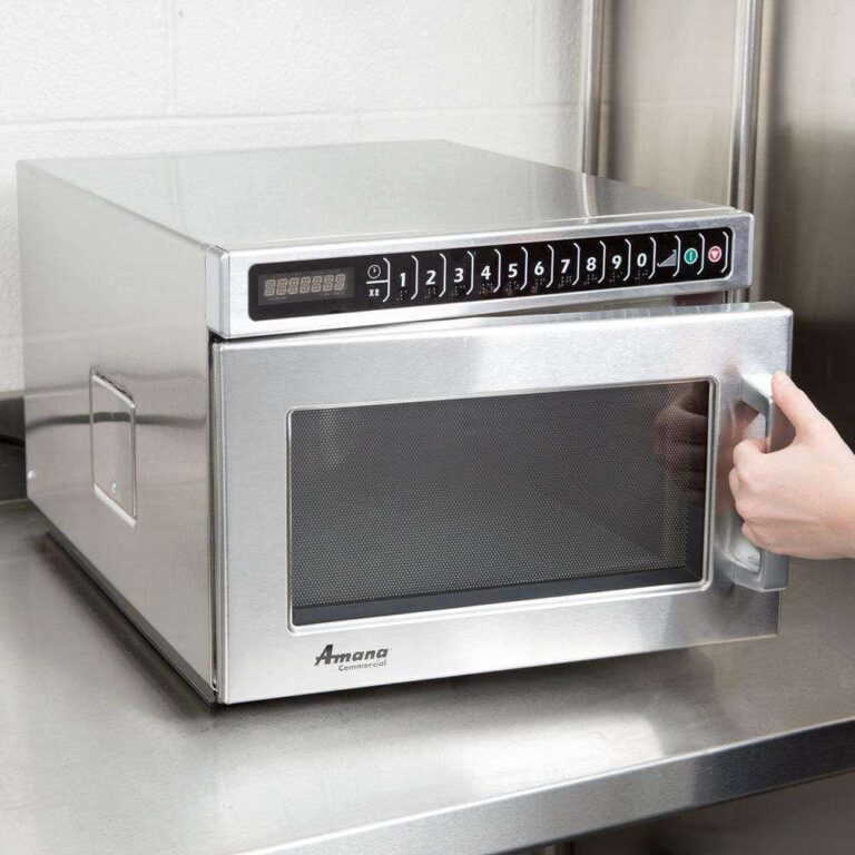 Amana commercial microwave oven in stainless steel kitchen, technician opening door for inspection in Tampa