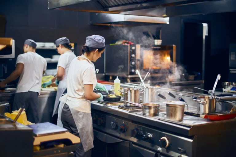 Restaurant hot line with chefs cooking on commercial stoves and steam rising in Tampa kitchen