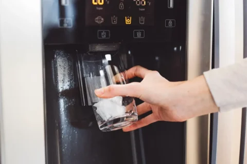 Refrigerator ice maker and water dispenser dispensing ice into a glass